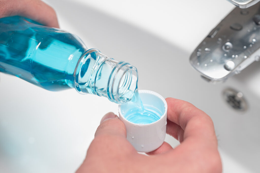 Man pouring mouthwash into mouthwash cap