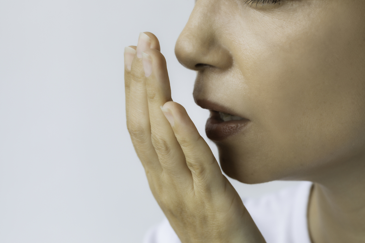 Unrecognizable female is checking smell of breath