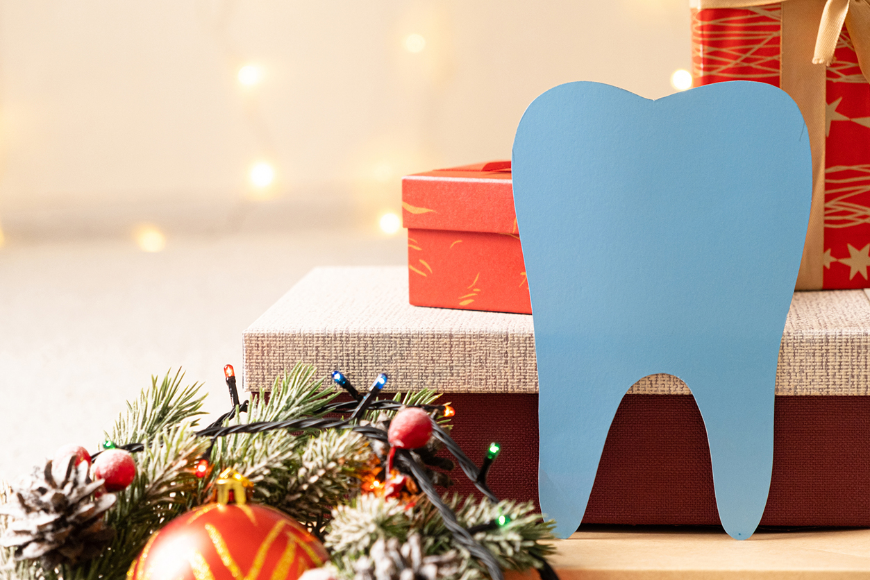 Holiday Gift Ideas - Dental Gifts - tooth on the background of flashing garlands and gift boxes.