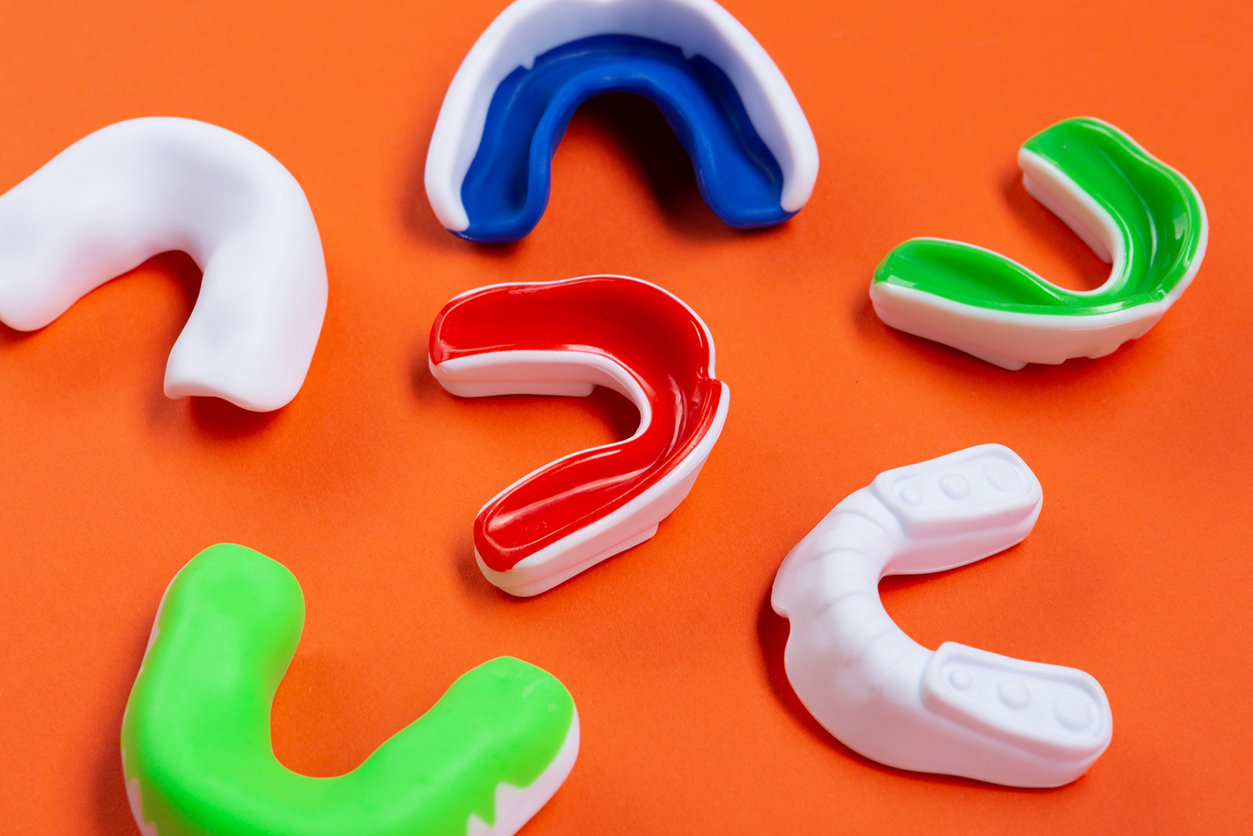 Lots of boxing protective Winter Sports Mouthguards - mouthguards on orange background, concept