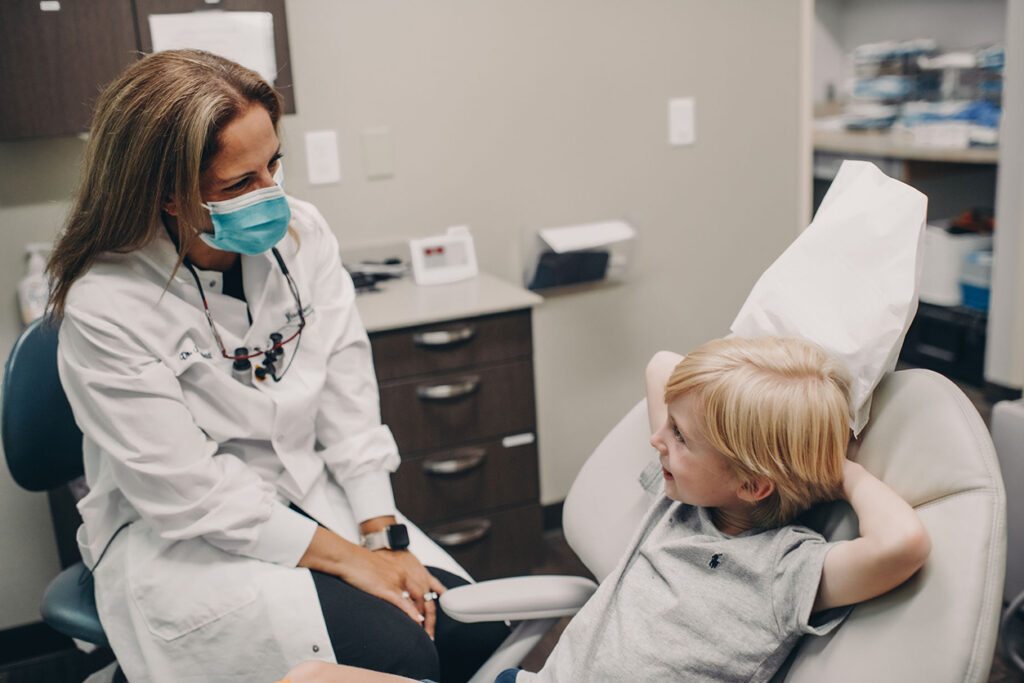 Child in dental chair talking with doctor