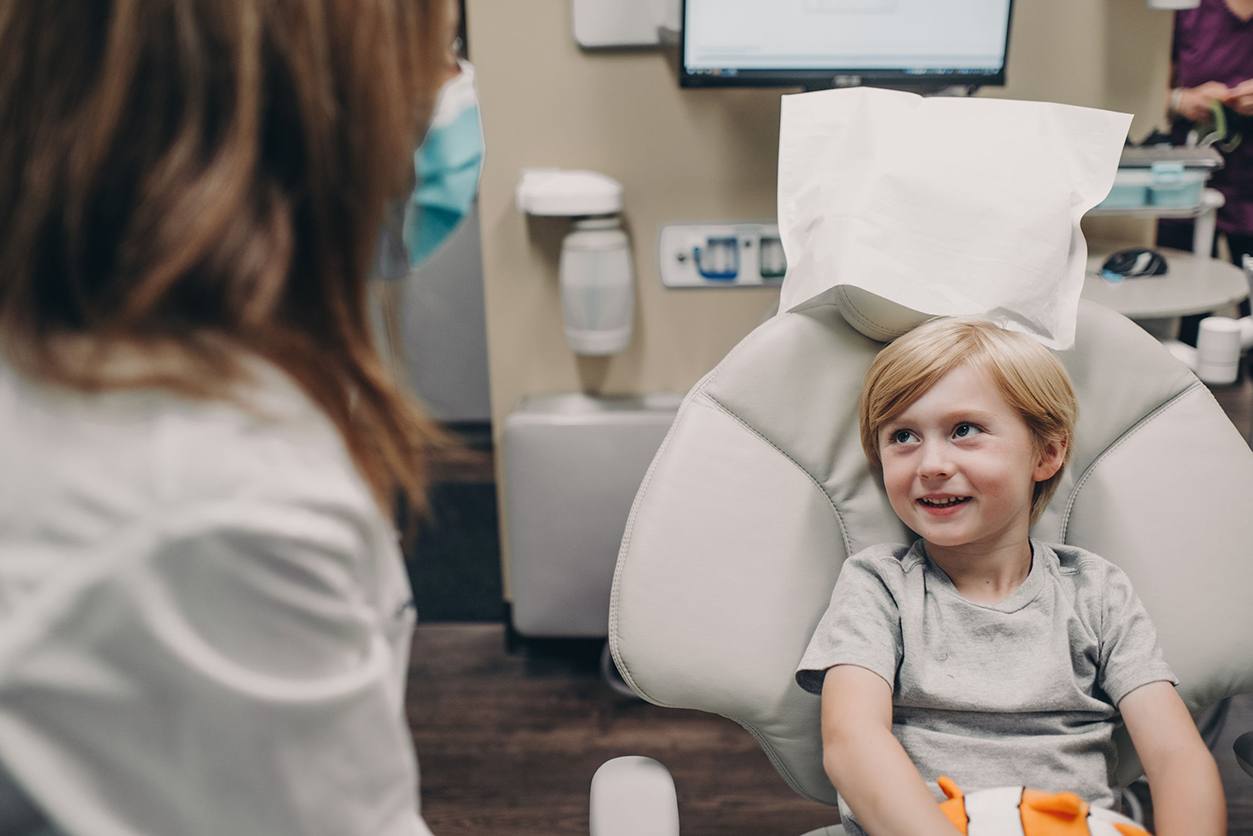 Child in dental chair talking with doctor