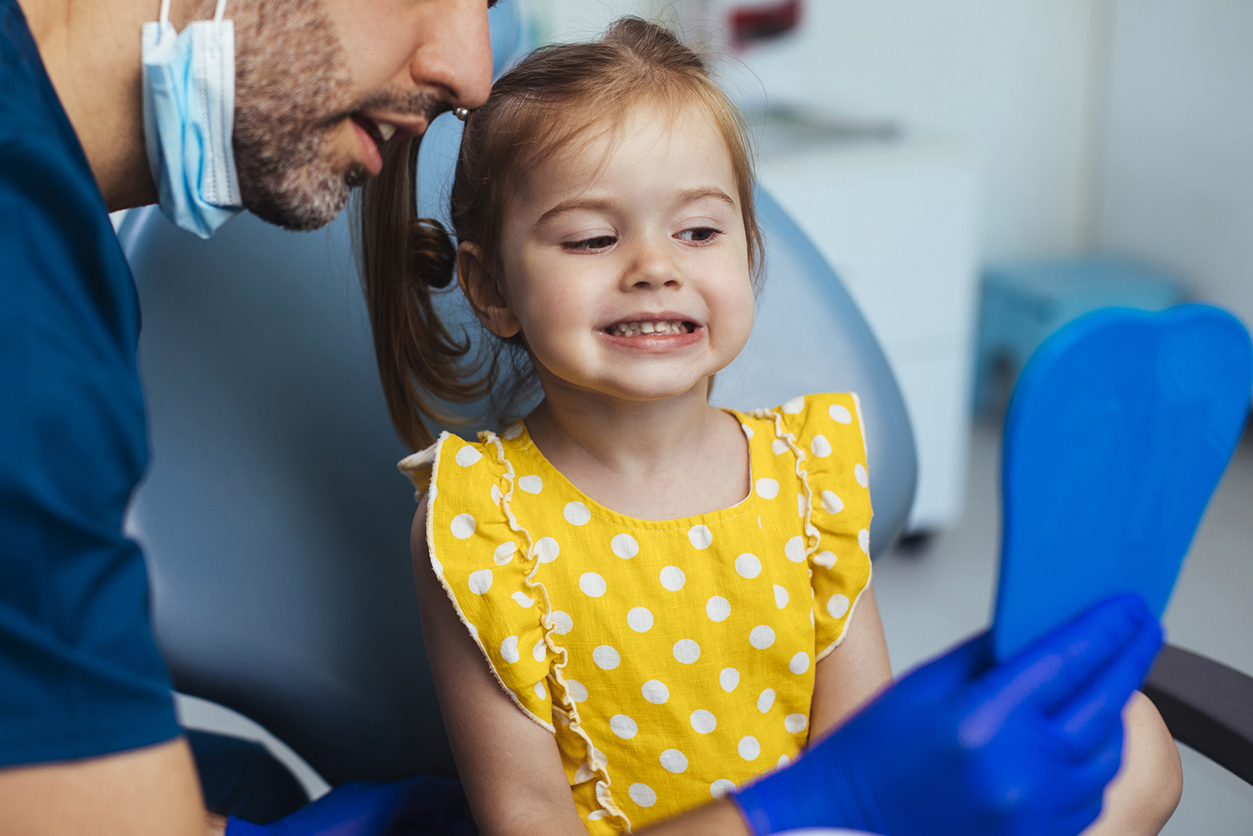 Young girl looking at a mirror after having a routine checkup at the dentist