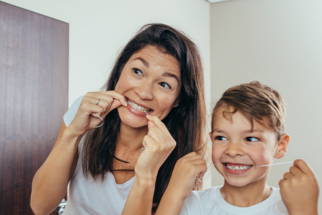 Woman with son looking in mirror and cleaning teeth.