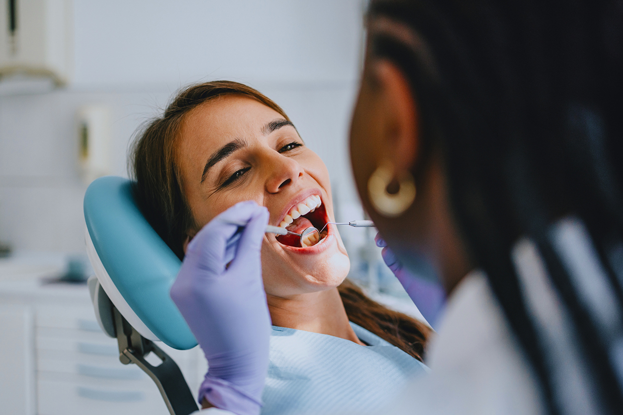 What’s Covered by Dental Insurance - Young Woman Receiving Dental Checkup from Dentist in Clinic