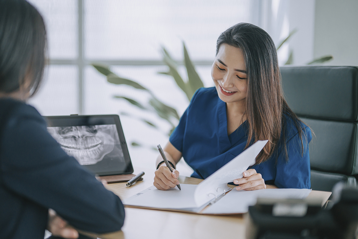 What’s Covered by Dental Insurance - Female dentist explaining medical x-ray image To a female Patient in her office