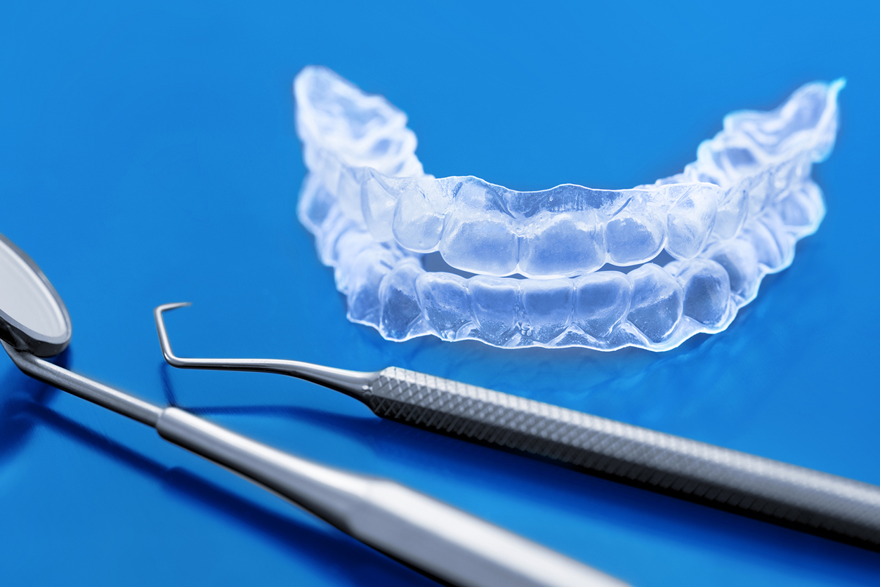 Veneers vs. Invisalign - Plastic braces dentistry retainers with dental tools