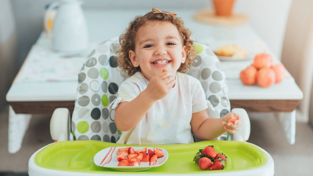 smiling young child eating a health snack for her body and smile