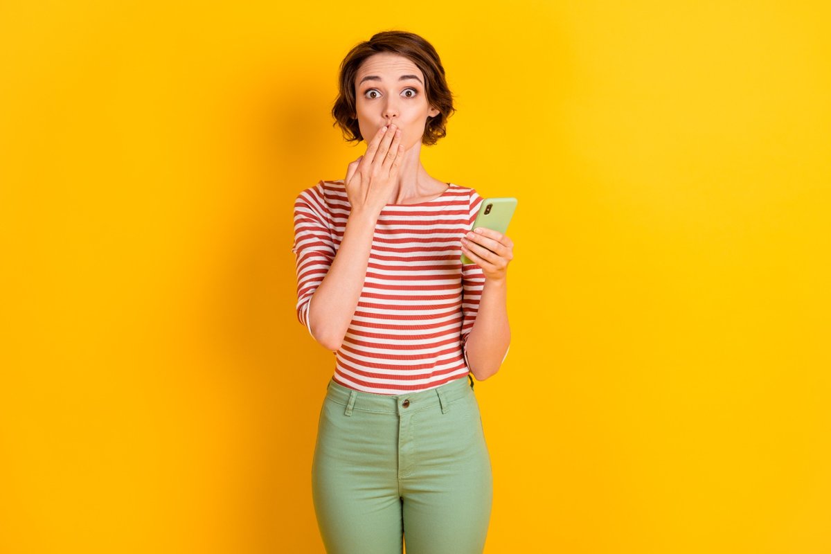Surprised woman holding smartphone after discovering a lost dental filling.