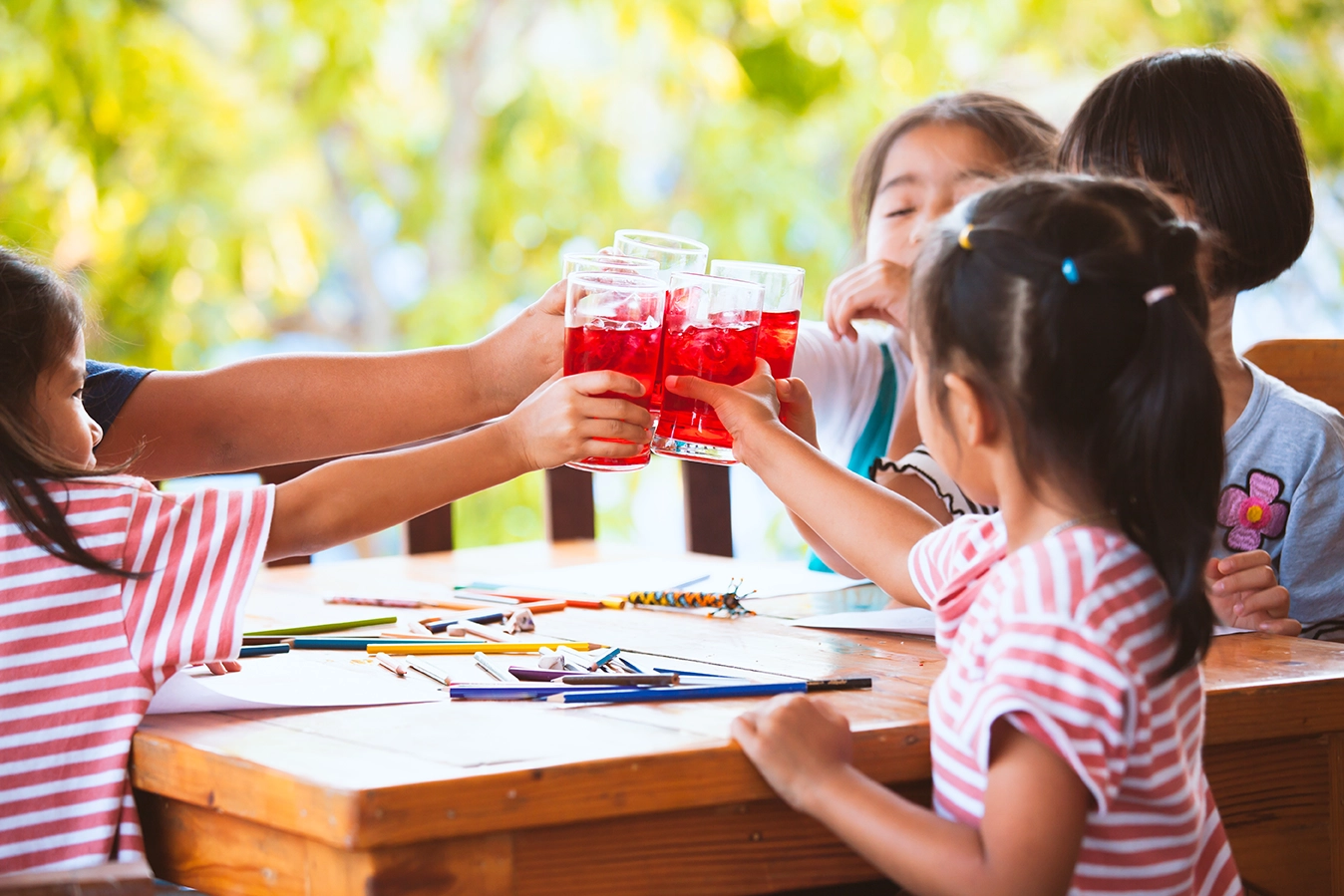 Children toasting with glasses of red juice during an outdoor art activity