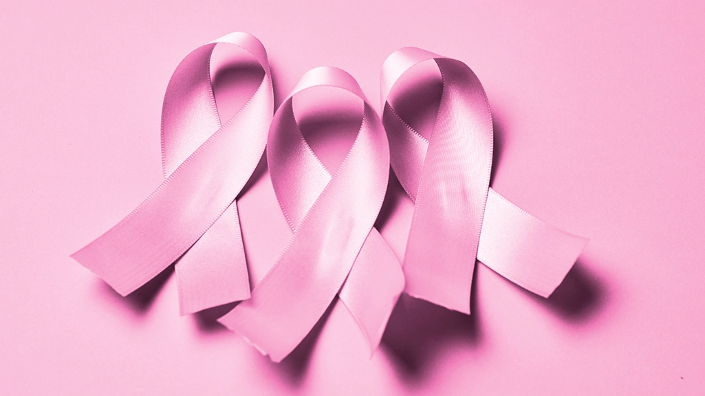 Close-up of three pink breast cancer ribbons on a pink background