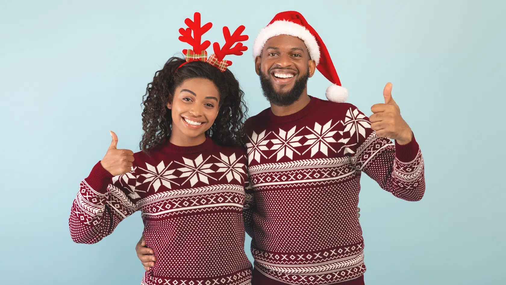Smiling couple in christmas sweaters receiving the gift of cosmetic dentistry