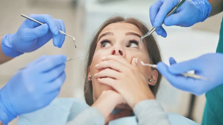 Woman with hands over her mouth showing she is anxious at the dentist