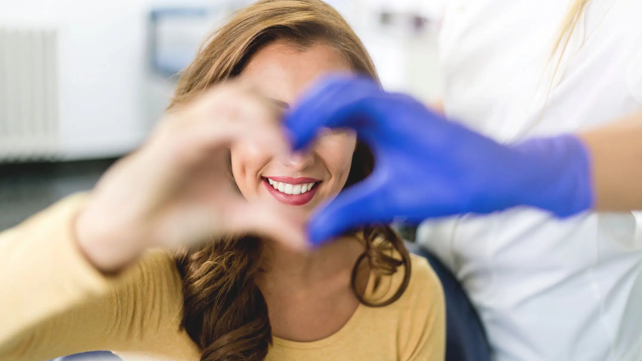 Making heart with hands at dentist showing dental anxiety has disappeared