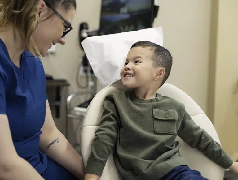 Child smiling in a dental chair next to the hygienist