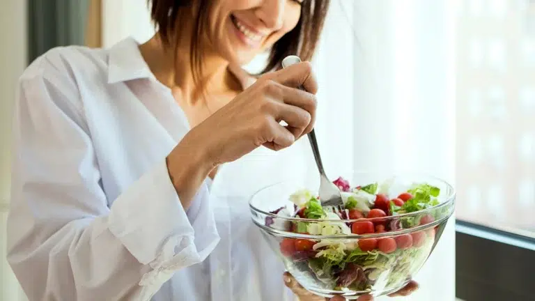 Smiling woman eating a heart healthy salad, good for your smile too