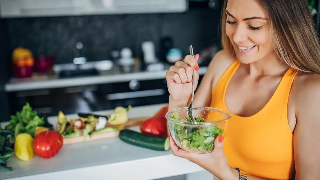 Woman eating a salad for heart health and a healthy smile
