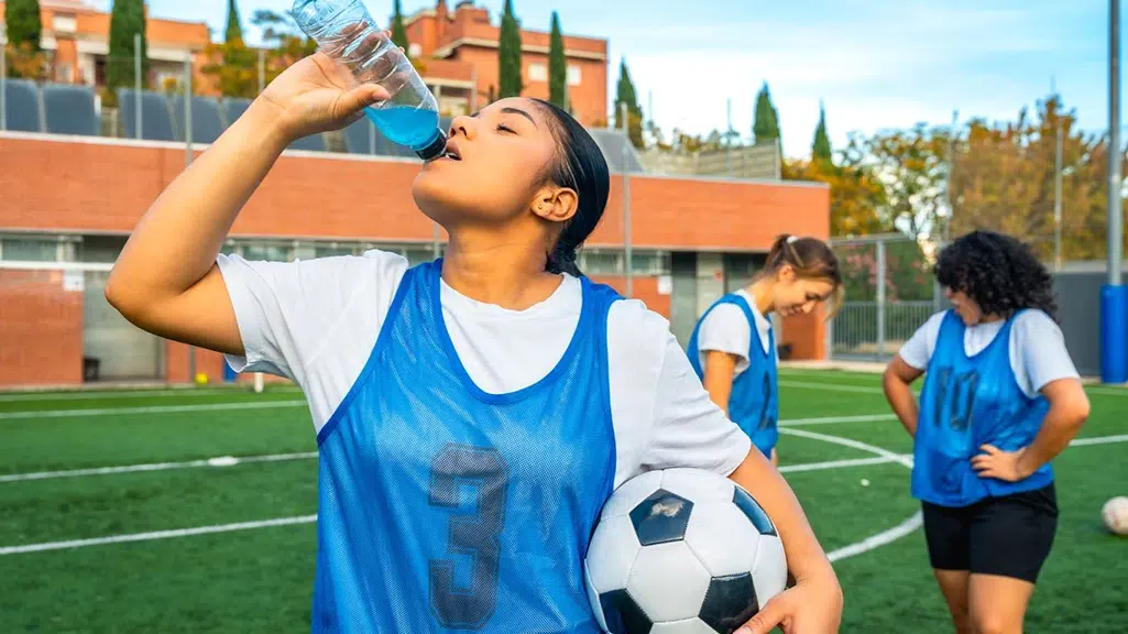 Young girl drinking sports drink at soccer practice