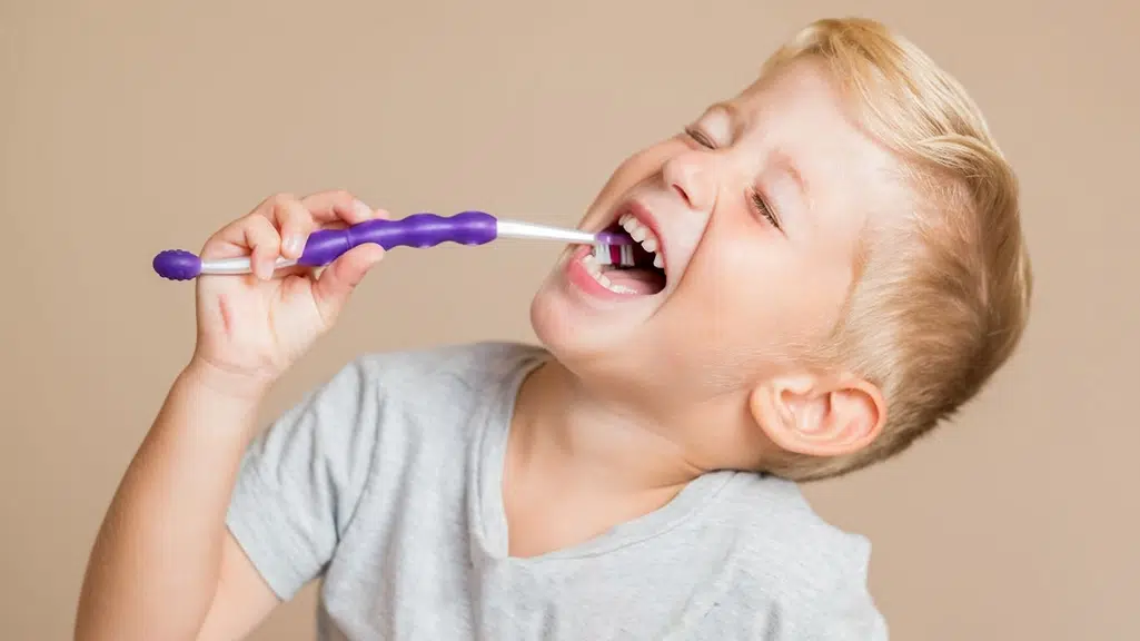 Young blond boy brushing his teeth