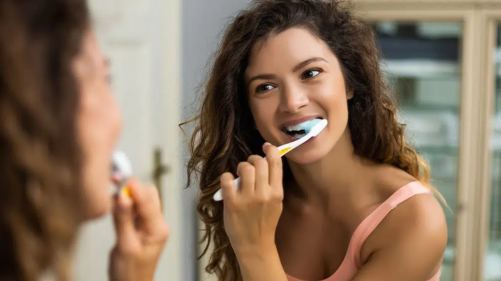 Young teen with dark hair brushing here teeth