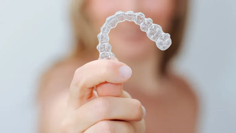 Clear Invisalign-style dental aligner held in front of a patient